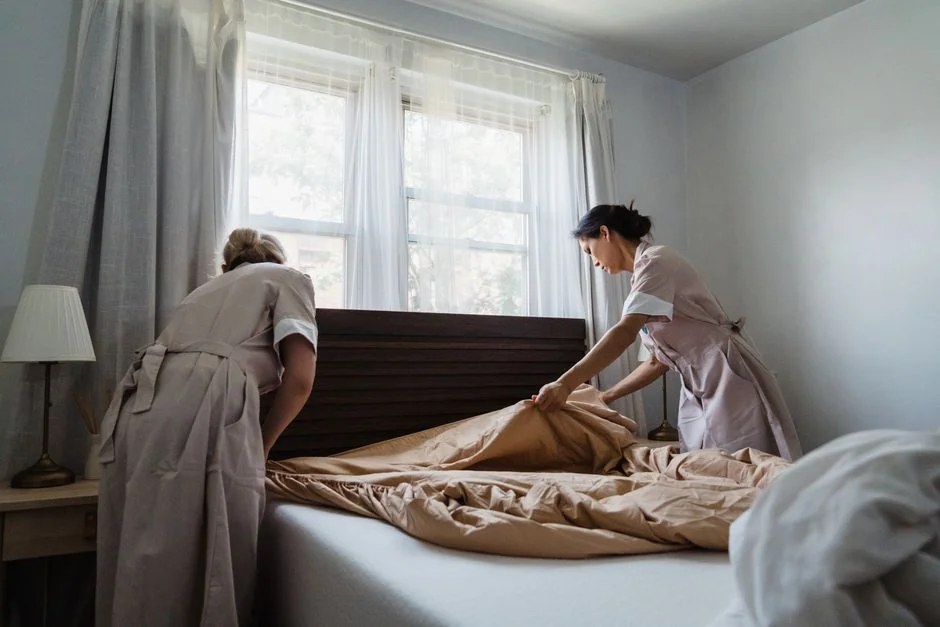 A woman carefully covers a sofa with protective material while packing boxes in a bright room.